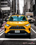 A yellow New York taxi viewed head-on against a largely black-and-white city street. Photograph by Anders Jorulf.