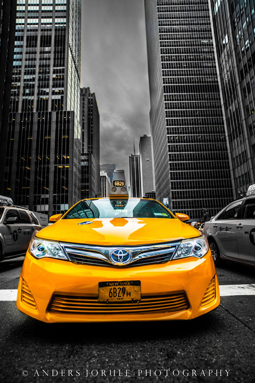 A yellow taxi facing the camera between New York’s tall, largely monochrome buildings. Photograph by Anders Jorulf.