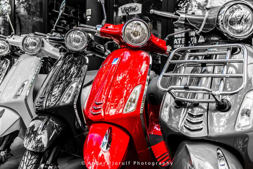 A red scooter among largely black-and-white parked scooters in Paris. Photograph by Anders Jorulf.