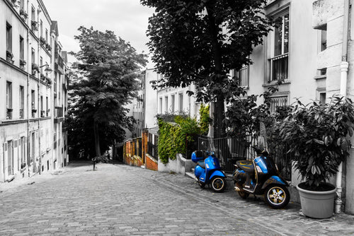 A Paris cobbled street with parked scooters and touches of blue and green. Photograph by Anders Jorulf.